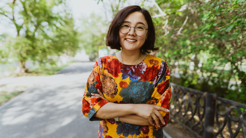 Smiling woman in bright top on nature trail.