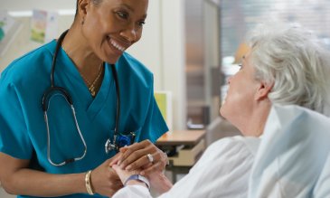 nurse holds hands with older female patient
