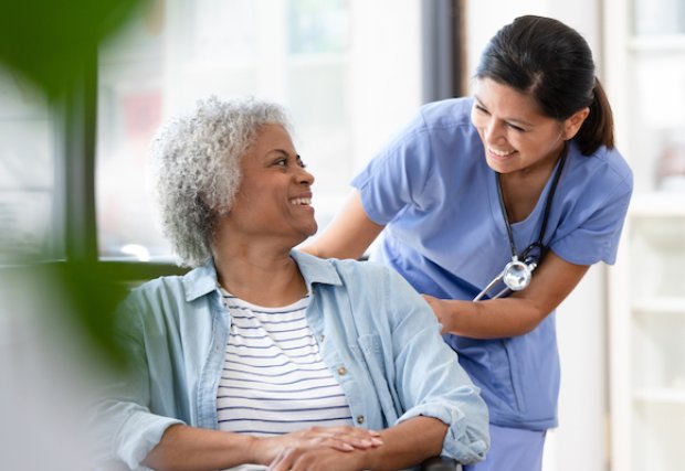 Female patient in wheelchair smiling at female nurse