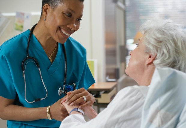nurse holds hands with older female patient