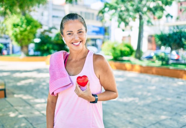 Woman smiles holding heart at the park