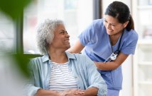 Female patient in wheelchair smiling at female nurse