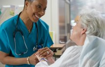 nurse holds hands with older female patient