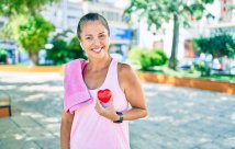 La mujer sonríe sosteniendo el corazón en el parque